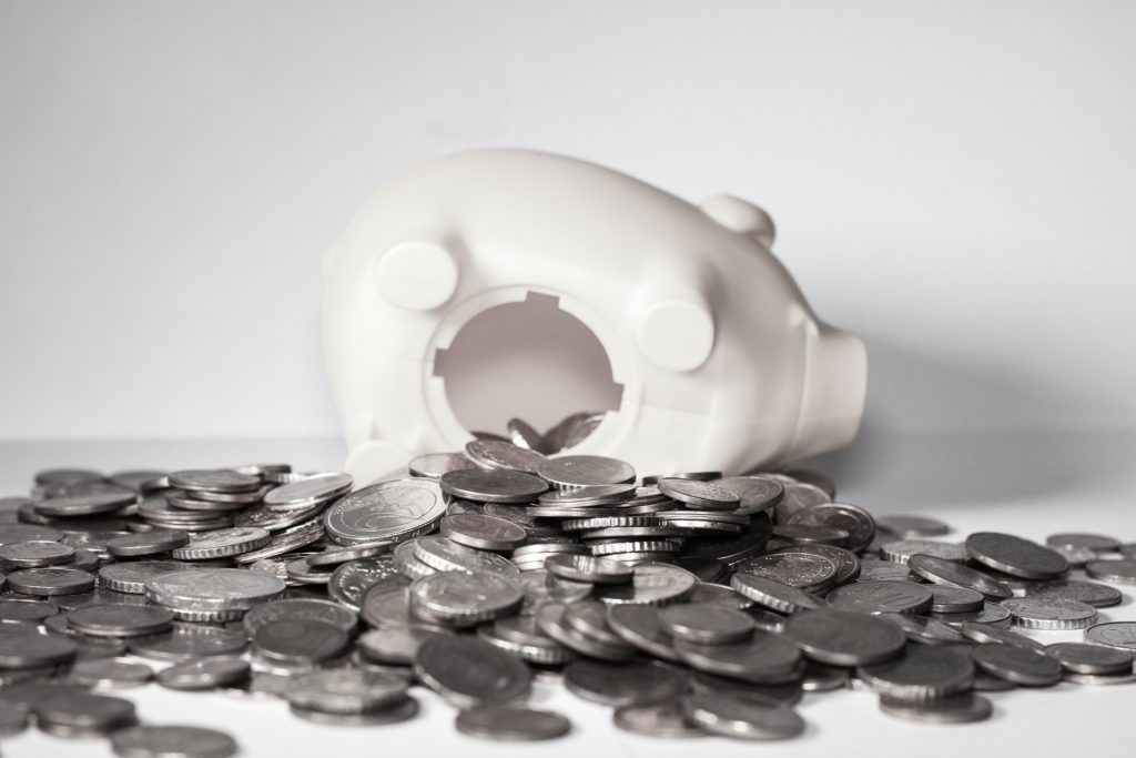 Budgeting Tips Piggy Bank tipped over with coins spilling out